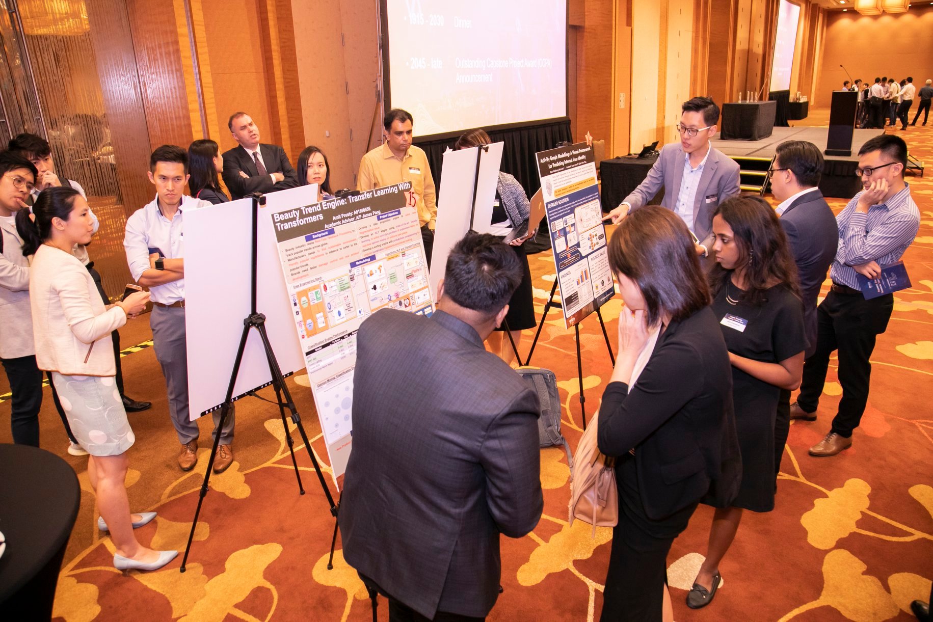 Graduating students standing by their proposed solution for used case presented via poster sharing to audience their works.